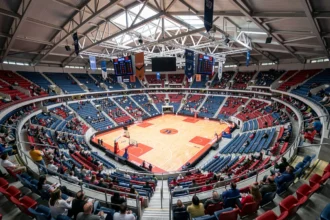 Vue panoramique de l'Accor Arena Paris depuis les gradins supérieurs lors d'un événement sportif, montrant le plan de salle complet avec les rangées de sièges colorés et le parquet central