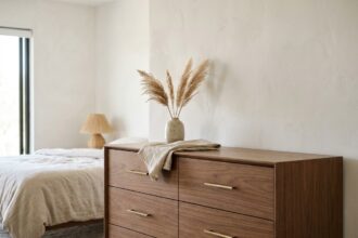 Commode en bois de noyer style mid-century dans une chambre moderne avec vase en céramique et quincaillerie dorée