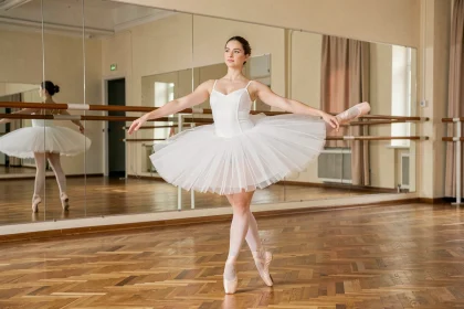 Danseuse de ballet en arabesque dans un studio de danse classique avec miroirs et parquet